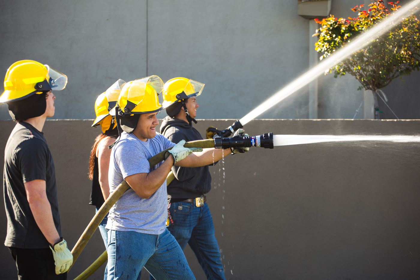 Students practice with a fire hose during hands-on training