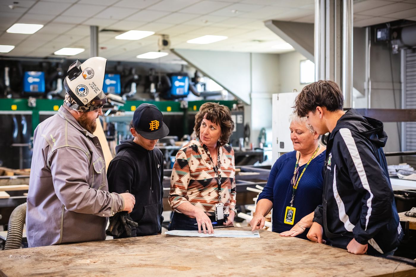 Program staff work with students at a shop table